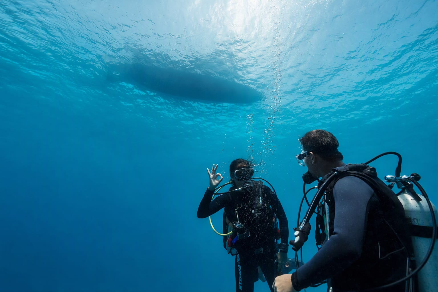 Two divers giving each other the OK sign just below the surface